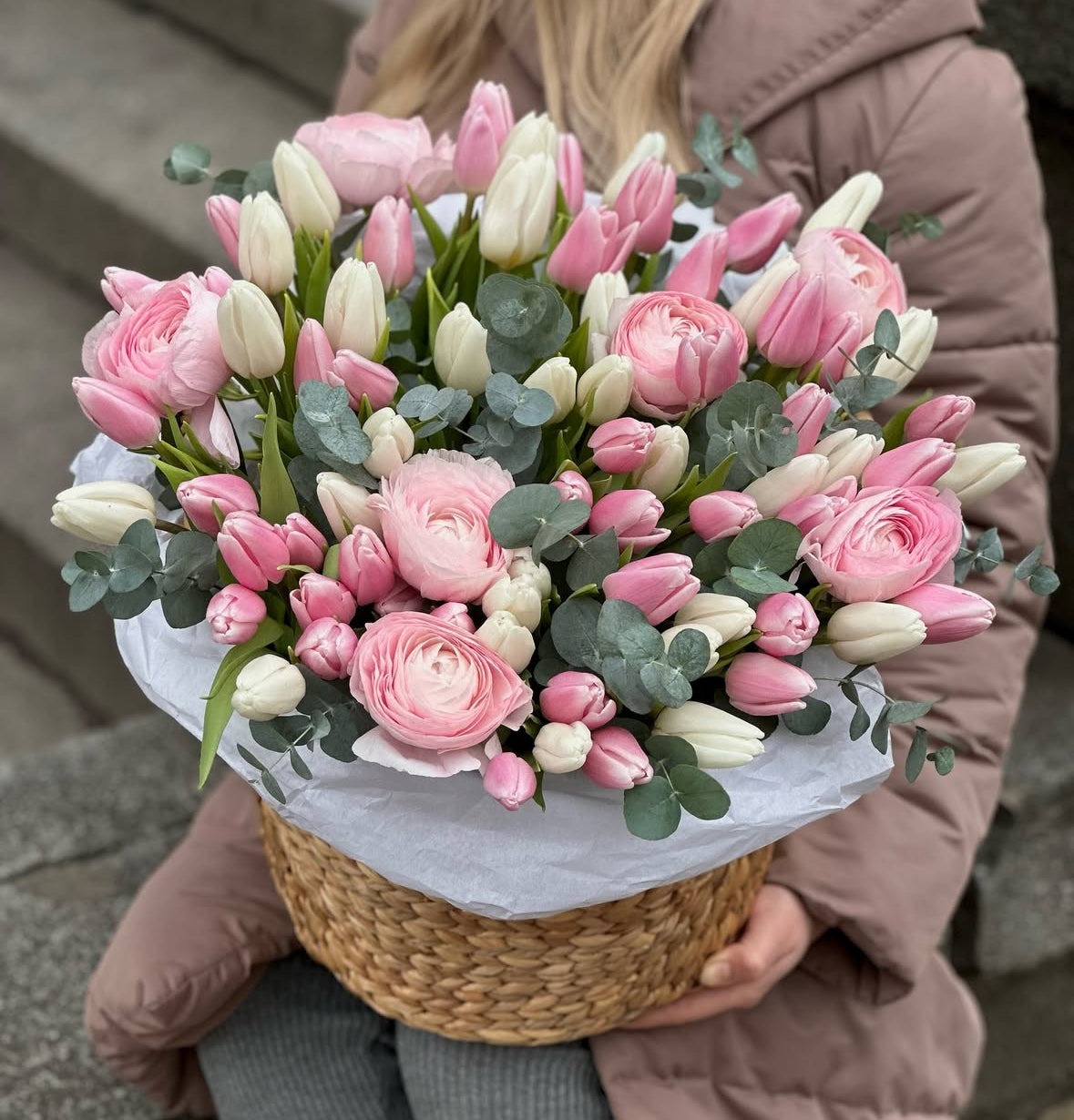 Arreglo floral en cesta con ranúnculos y tulipanes blancos y rosas