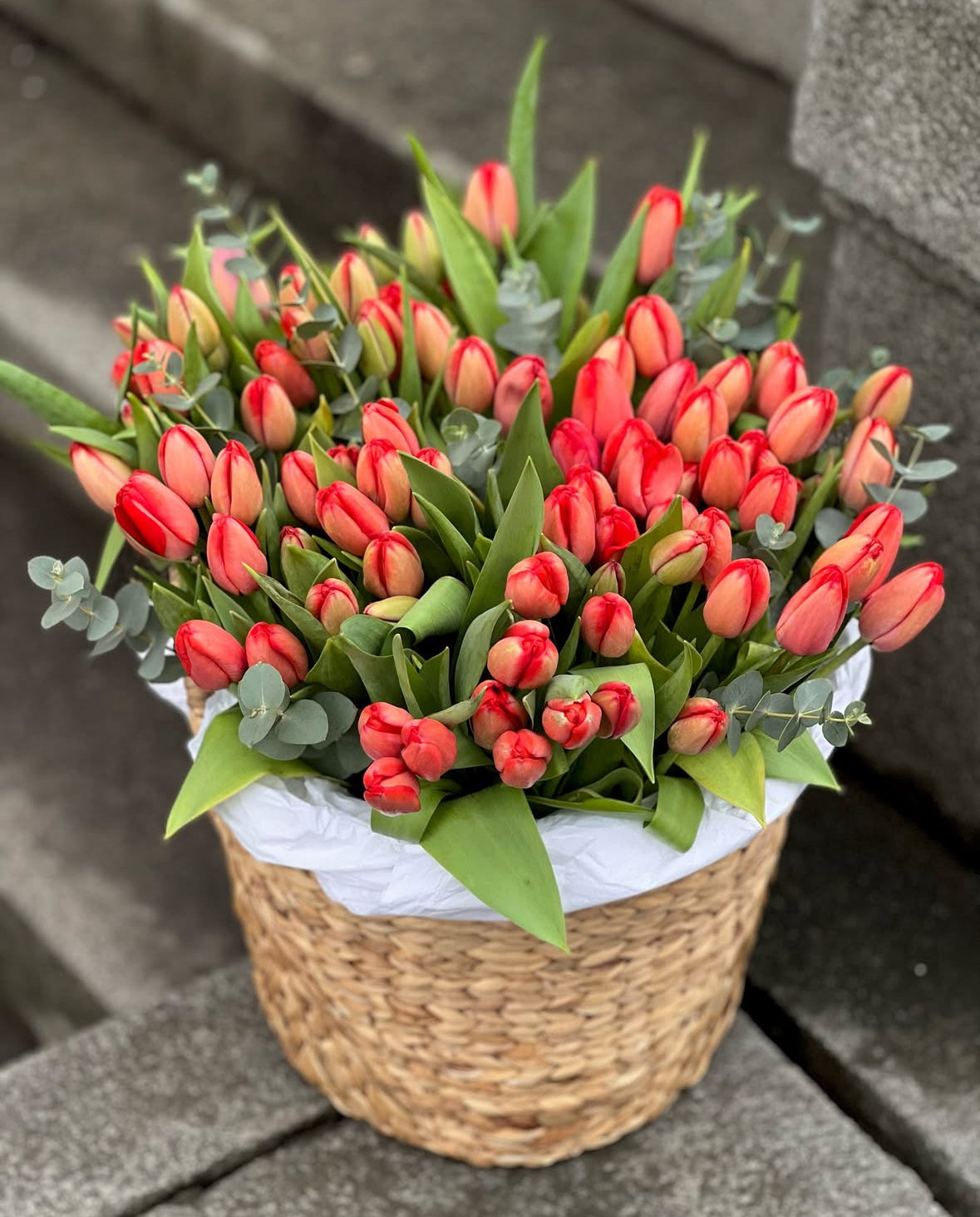 Tulipanes rojos y rosas en cesta artesanal